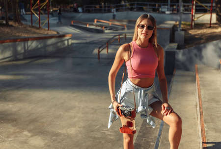 Young fashionable blonde woman with retro camera outdoorsの写真素材