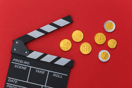 Film clapper board with coins on red background. Cinema industry, entertainment. top viewの写真素材