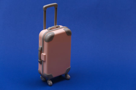 Travel or trip concept. Mini plastic travel suitcase on classic blue background. Color 2020