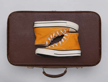travel concept. Retro style sneakers and old travel suitcase on white background. top view. flat lay