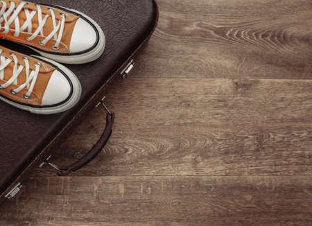 travel concept. Retro style sneakers and old travel suitcase on wooden floor. top viewの写真素材
