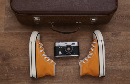 travel concept. Retro style sneakers and old travel suitcase, camera on wooden floor. top viewの写真素材