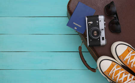 travel concept. Retro style sneakers and old travel suitcase, accessories on blue wooden background. top viewの写真素材