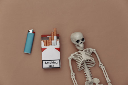 Pack of cigarettes and skeleton on brown background. bad habit. Smoking killsの写真素材