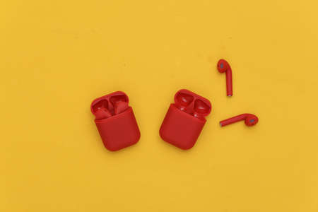 Two pair of Red wireless headphones with charging case on a yellow background. top view