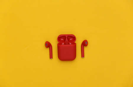 Red wireless headphones with charging case on a yellow background. top viewの写真素材