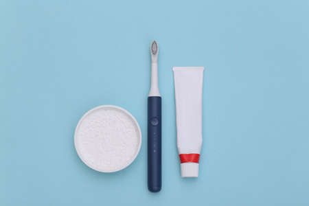 dental care. Tube of toothpaste, toothbrush and tooth powder on blue background.