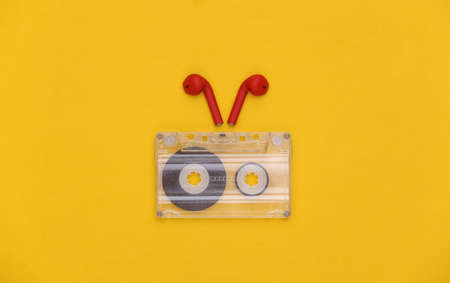Mini shopping cart and wireless headphones in case on yellow background