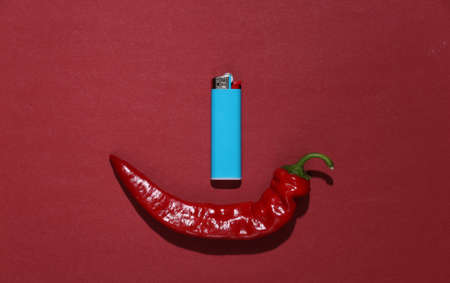Hot red chili peppers with lighter on red background