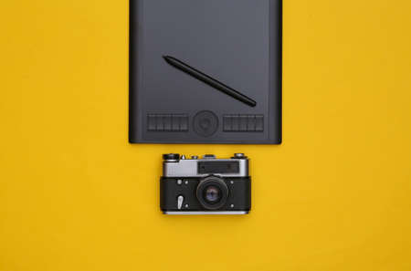 Graphic tablet with pen and camera on yellow background. top viewの写真素材