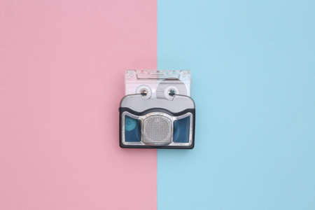 Mini audio cassette player with audio cassette on a blue pink background. top viewの写真素材