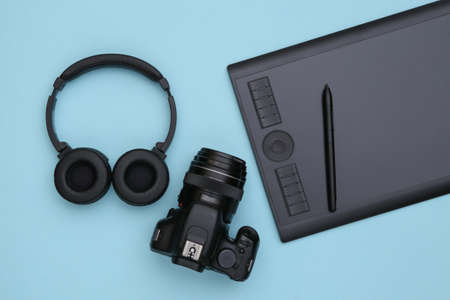 Graphic tablet with pen, headphones and camera on blue background. top viewの写真素材
