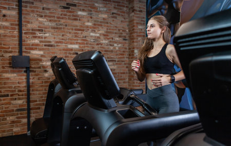 Slim beautiful Woman doing cardio training on treadmill, working out in gym