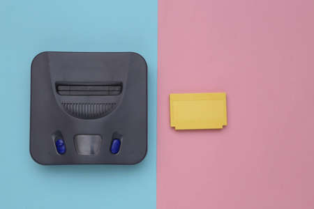Retro video game console, cartridge on blue pink background. top viewの写真素材