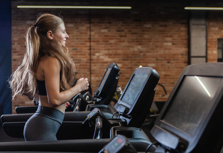 Slim beautiful Woman doing cardio training on treadmill, working out in gymの写真素材