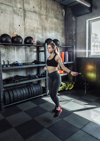 Attractive athletic woman jumping rope in gym