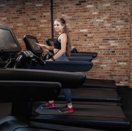 Slim beautiful Woman doing cardio training on treadmill, working out in gym