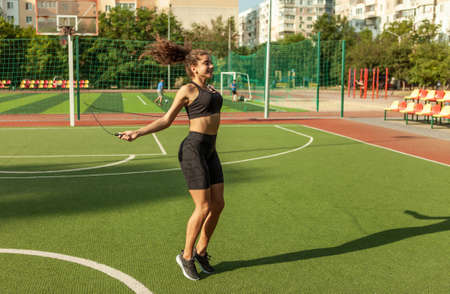 Fit woman in sportswear jumping rope outdoorsの写真素材