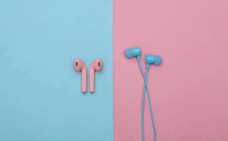 Wireless and wired headphones on a pink-blue pastel background. top view