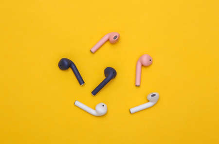 Different colors Wireless headphones on yellow background. top view. minimalism