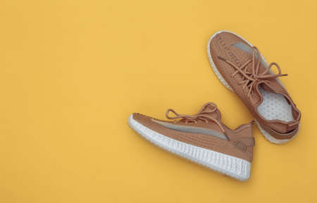 Brown textile sports shoes on yellow background. top viewの写真素材