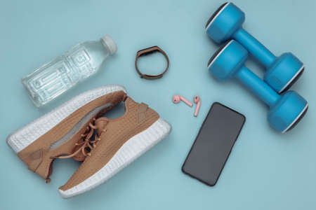 Flat lay composition of fitness accessories on a blue background. top view