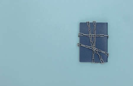 Passport wrapped in a metal chain on blue background. top viewの写真素材