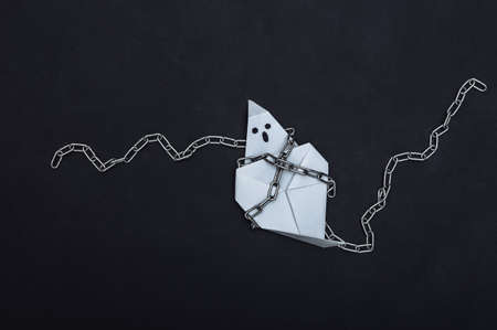 Origami ghost with steel chains on back background. Halloween themeの写真素材