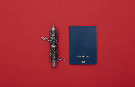 Pen wrapped in a steel chain and passport on red background. top viewの写真素材