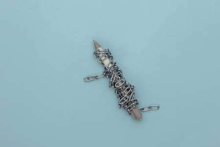 Pen wrapped in a steel chain on a blue background. top view