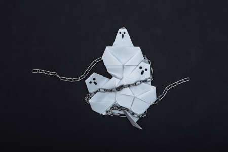 Origami ghosts with steel chains on back background. Halloween themeの写真素材