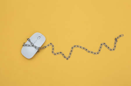 Pc mouse wrapped in steel chain on yellow background. top viewの写真素材