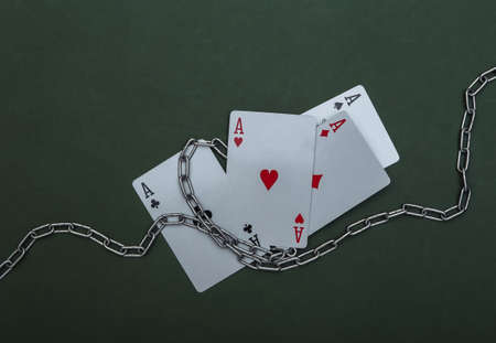 Four aces wrapped in a steel chain on green background. Prohibition of gambling business, casinosの写真素材