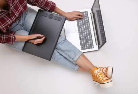 Graphic designer or photographer job. Woman works with graphic tablet and laptop while sitting on a...