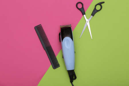 Barber tool on pink green background. Hair clipper, scissors and comb. top view. flat layの写真素材