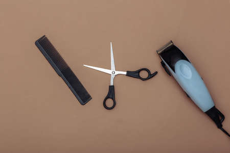 Barber tool on a brown background. Hair clipper, scissors and comb. top view. flat lay