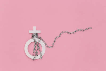 Gender female symbol wrapped in a steel chain on pink background. gender discrimination. top viewの写真素材