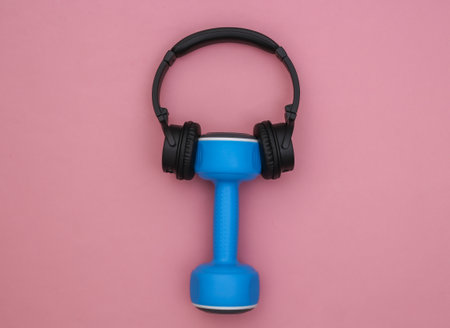 Dumbbell with stereo headphones on pink background. sport concept. top viewの写真素材