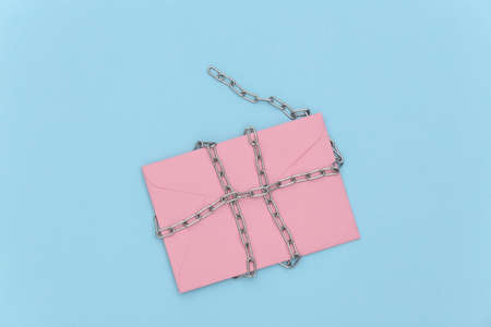 Envelope wrapped in a steel chain on a blue background. Secret letter protectionの写真素材