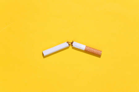 One Broken cigarette on yellow bright background. Quitting smokingの写真素材
