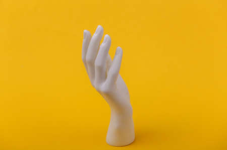 White mannequin hand on yellow background. Minimalism fashion concept
