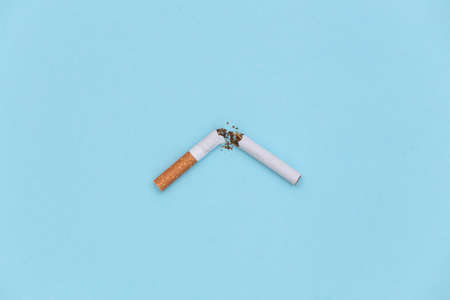 Broken cigarette on a blue background. Quitting smokingの写真素材