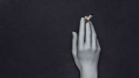 Mannequin hand holding cigarette on black backgroundの写真素材