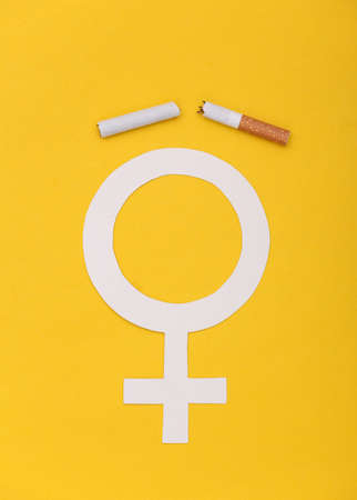 Broken cigarette and female venus symbol on yellow background. Quitting smoking