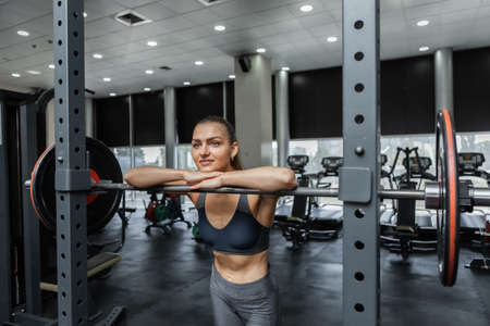 Young athletic woman resting leaning on barbell in gymの写真素材