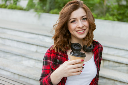 Young attractive hipster woman holding a cup of coffee outdoors.の写真素材
