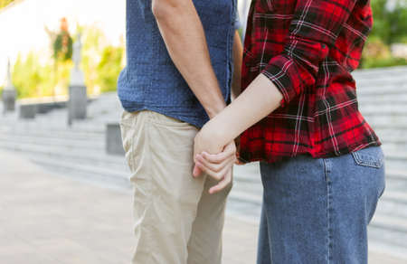 Close-up of the hands of a young couple holding each other outdoors. love concept