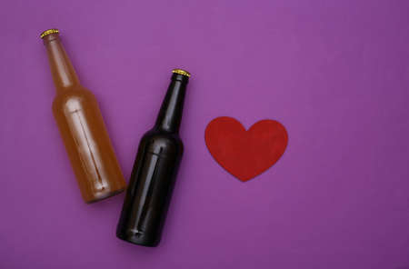 Beer lover. Two bottles of dark and light beer, heart on a purple background. top viewの写真素材