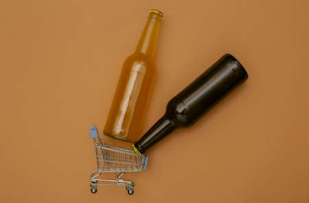 Mini shopping cart with bottles of beer on brown background. top view