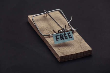 Mousetrap with free bait on black background. Traps, risks or deception concept